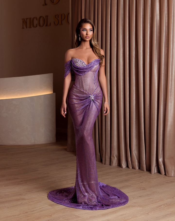 Woman in a purple evening gown standing in front of a curtain.